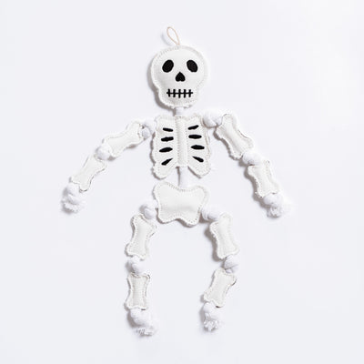 A durable white cotton canvas skeleton with cotton rope dog toy with black embroidered facial features and black rib details, shown against a plain white background.