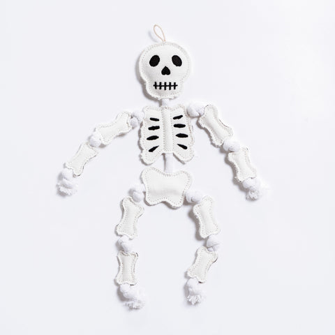 A durable white cotton canvas skeleton with cotton rope dog toy with black embroidered facial features and black rib details, shown against a plain white background.