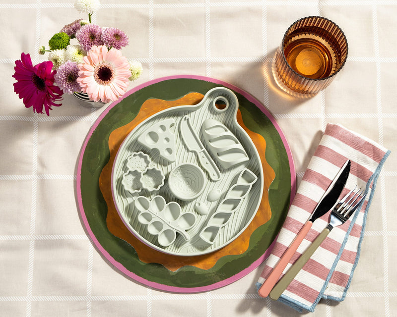 Decorative plate with floral arrangement and cutlery on a checkered tablecloth