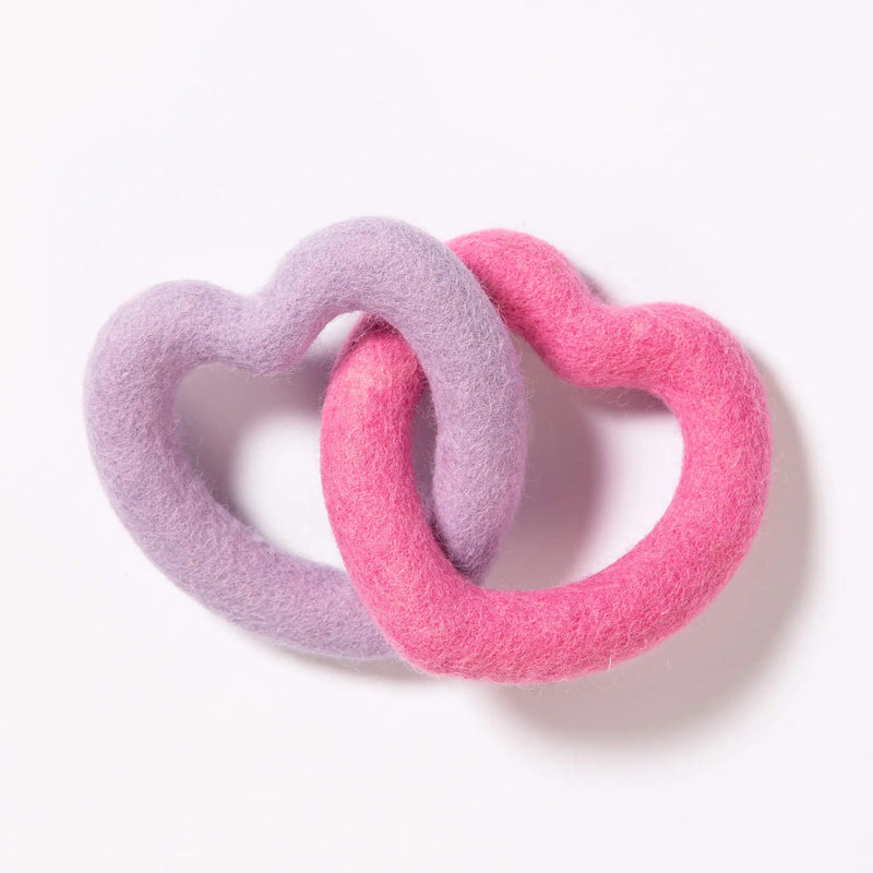Two heart-shaped felt dog toys, one pink and one purple, interlinked on a white background.